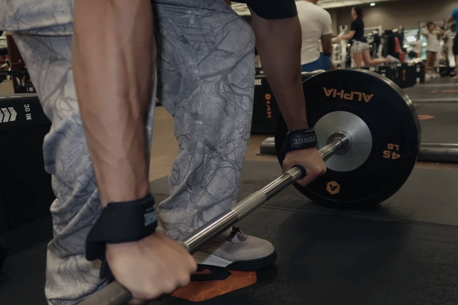 FORGE wrist straps secured around a loaded barbell before a pull