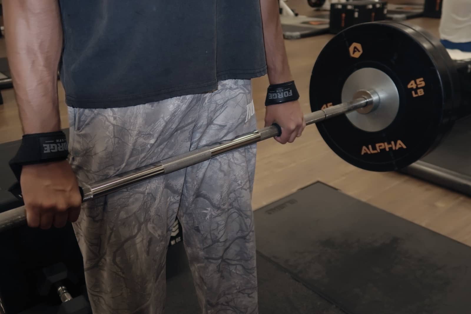 FORGE wrist straps on a lifter holding a loaded barbell