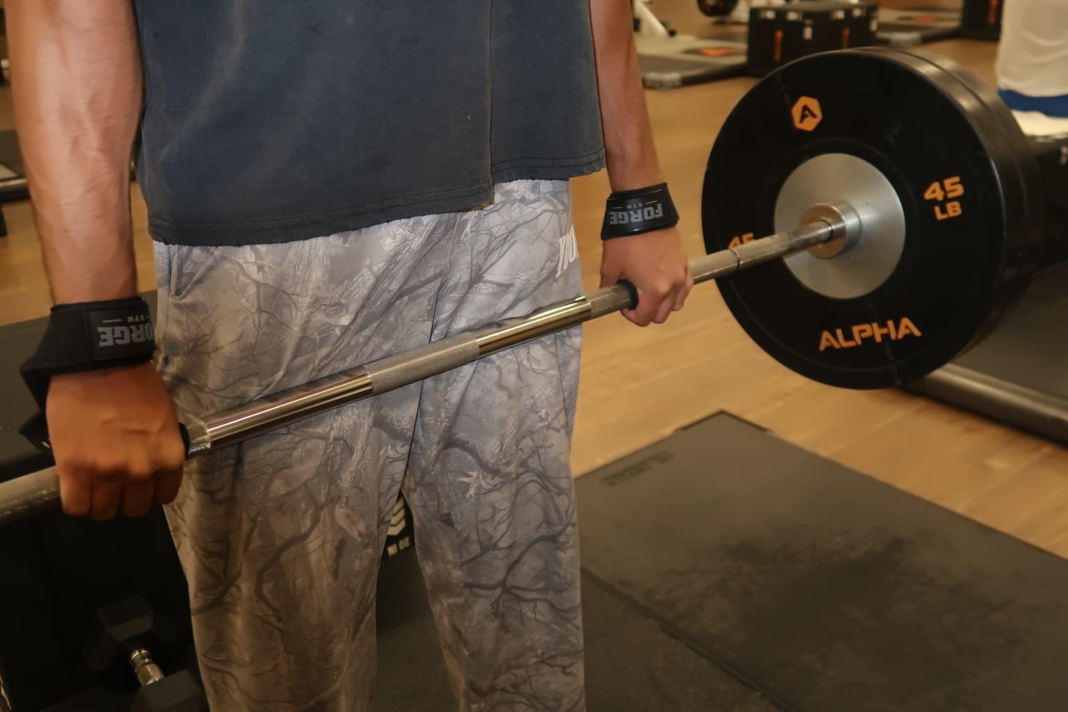 FORGE wrist straps worn while holding a loaded barbell.