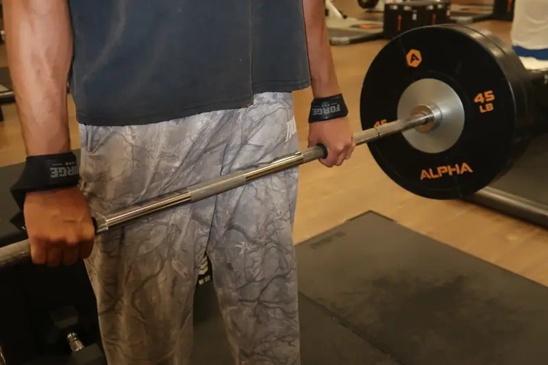 FORGE wrist straps on a lifter holding a loaded barbell
