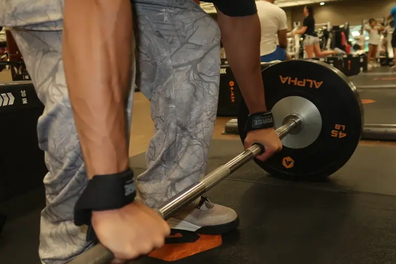 FORGE wrist straps secured around a loaded barbell before a pull
